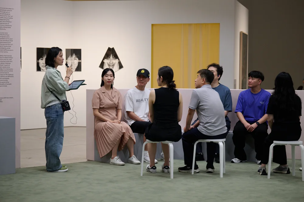 나란히 보는 미술관 참여자들이 함께 앉아 현장 음성해설을 듣는 모습